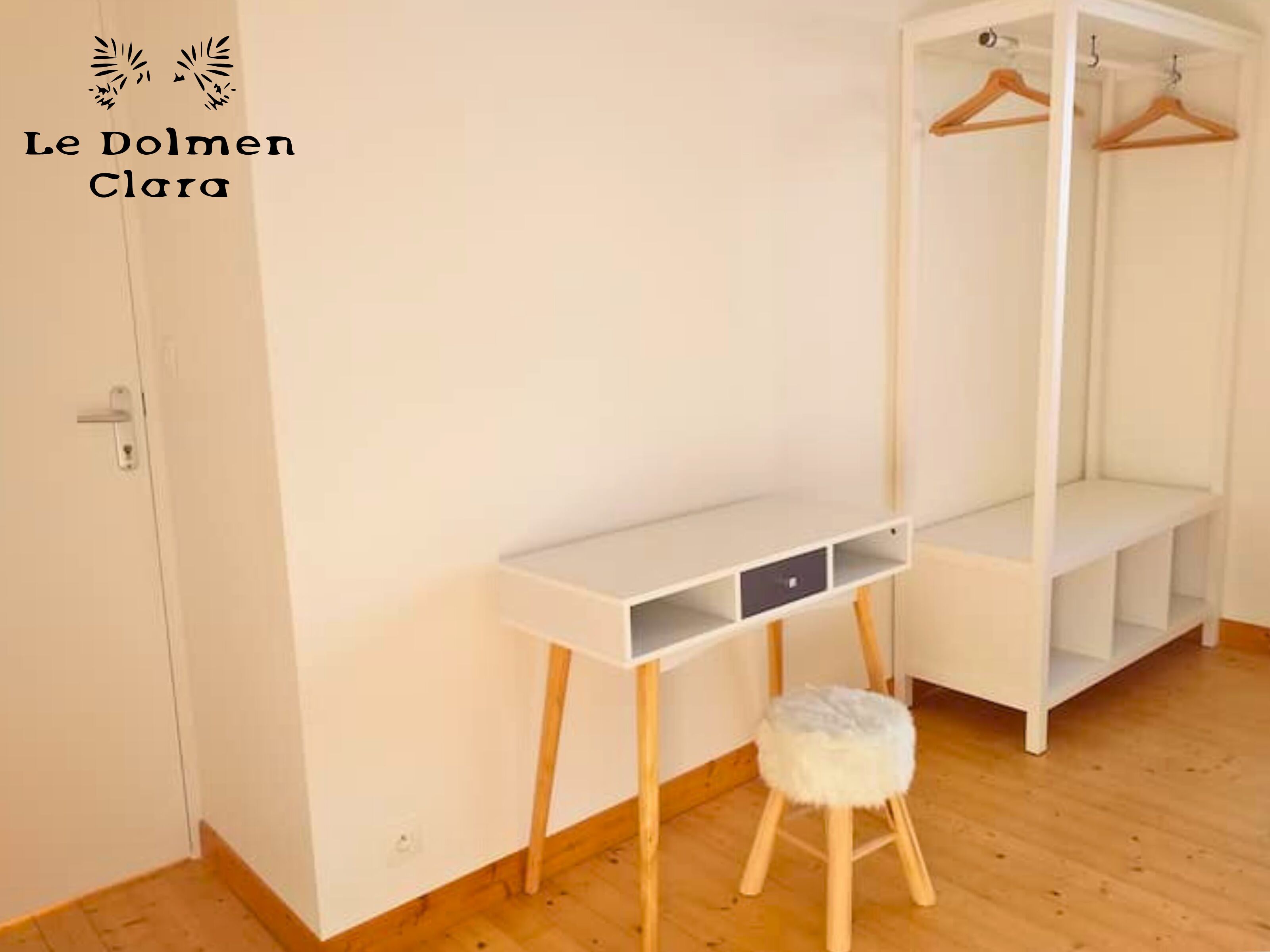 A white wardrobe with a mirror, a small stool, and a white shelf unit.