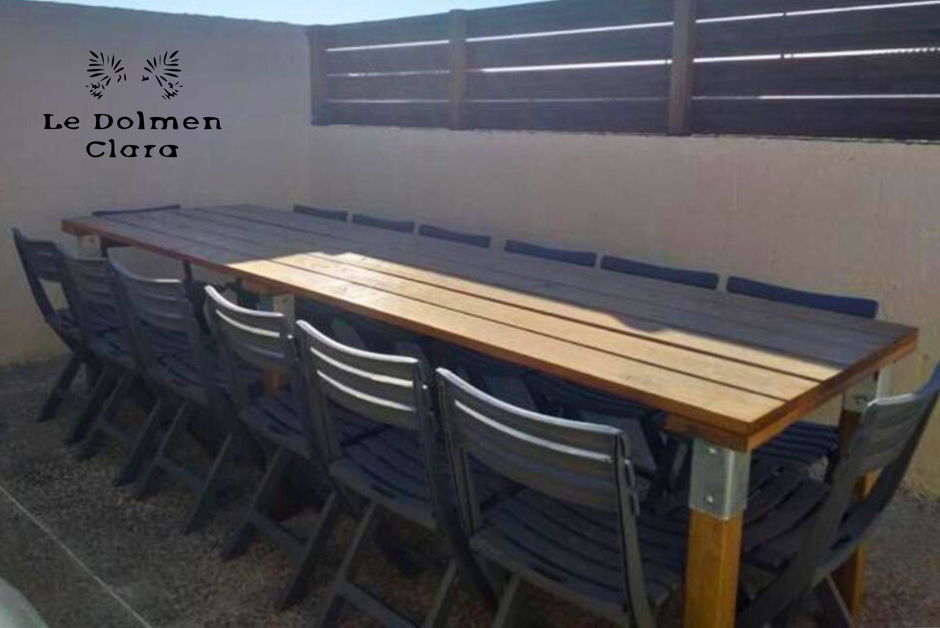 Een terras met een houten tafel en stoelen.