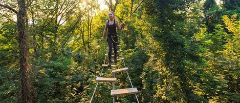 A person on a wooden climbing structure in a forested area.