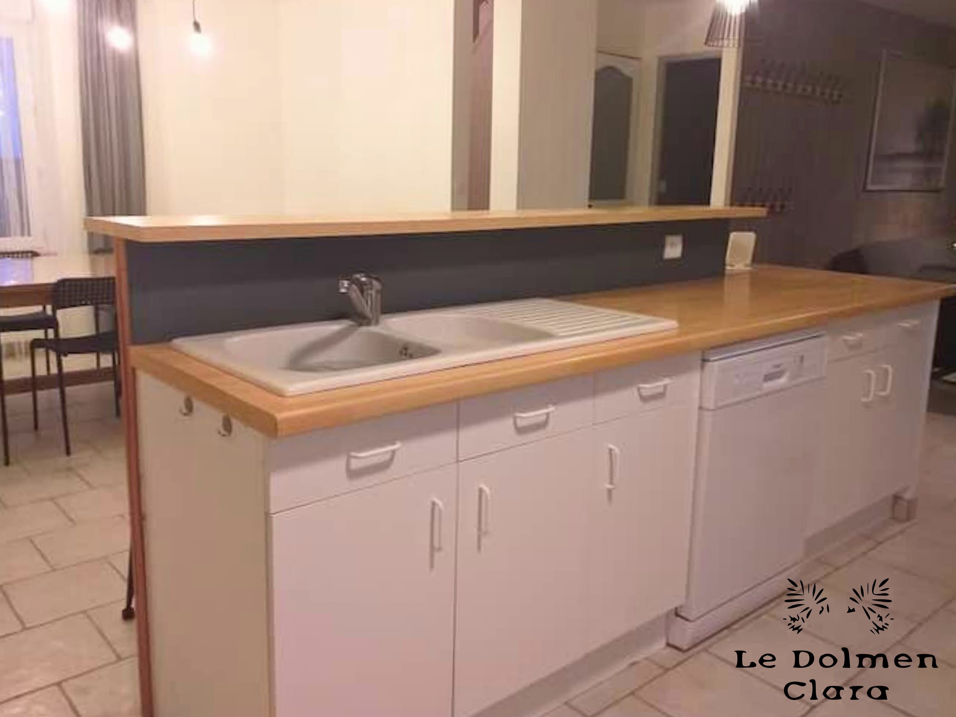 A kitchen with a wooden countertop, a sink, and white cabinets.