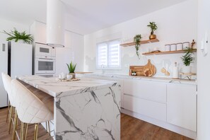 A modern kitchen with a marble island, white cabinetry, and a window with blinds. - Brand-new, luxury ***** villa with a barbecue and pool, just 7 km from the ocean (Jadreski)