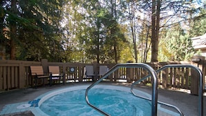 Une piscine dont le bord est revêtu de carrelage, entourée d’une terrasse en bois et de bancs.