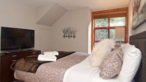 Une chambre à coucher avec un lit, une télévision et une fenêtre donnant sur des arbres.