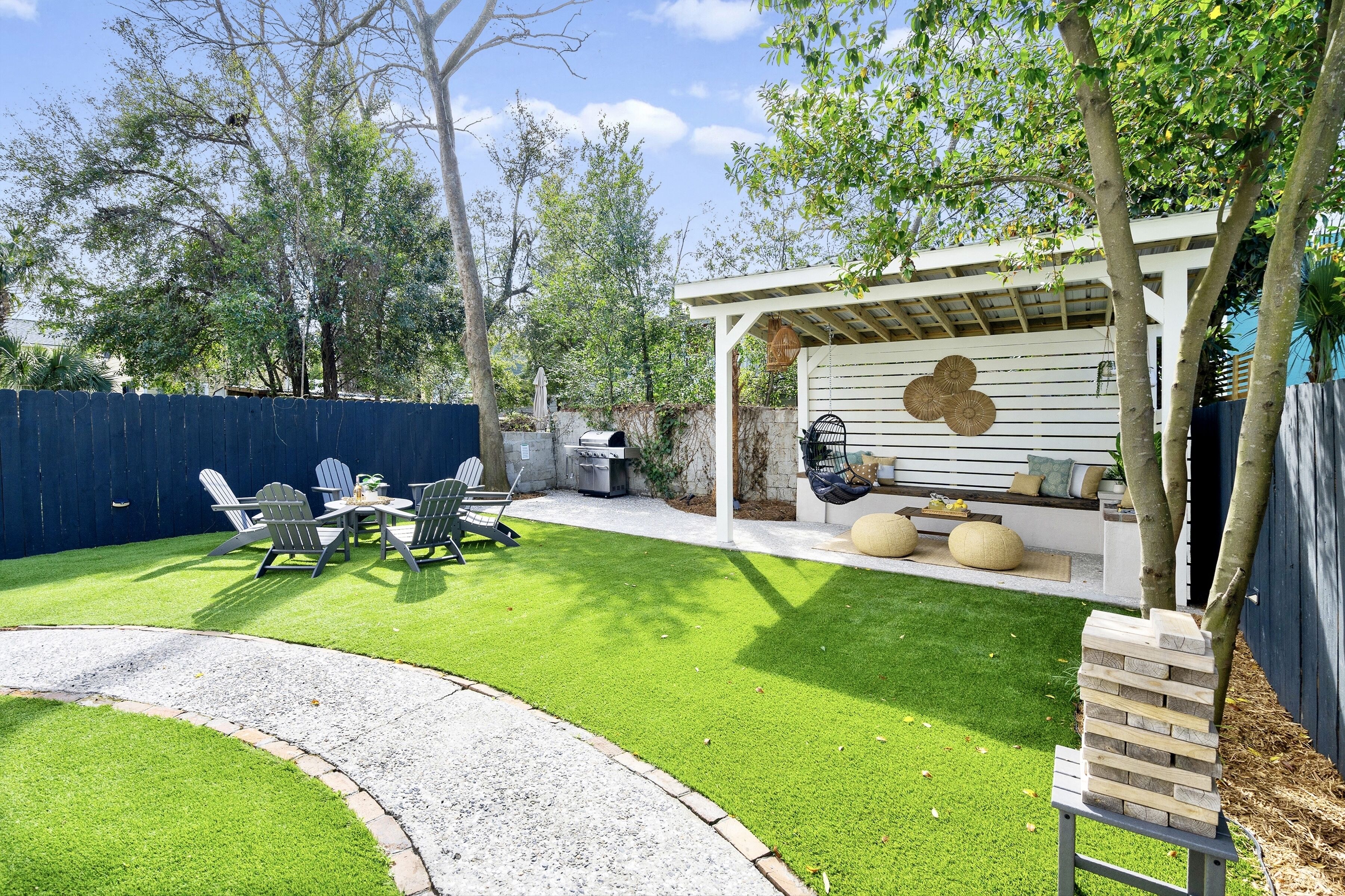 Un patio trasero con terraza, asientos exteriores y zona de barbacoa.