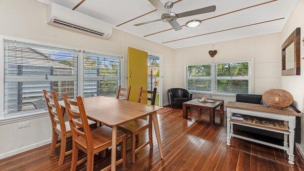Une pièce spacieuse comprenant une table à manger en bois, des chaises, un canapé et un ventilateur de plafond.