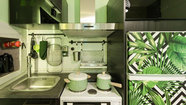A kitchen with a stainless steel range hood, a built-in oven, and a microwave. There is a sink with a faucet and a drying rack above it. - Emerald central luxury mini suite (Thessaloniki)