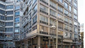 A multi-story building with a modern architectural design, featuring large windows and a ground-level commercial space. - Emerald central luxury mini suite (Thessaloniki)