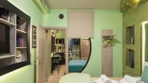A bedroom with a bed, a desk, and a bathroom visible through an open door. - Emerald central luxury mini suite (Thessaloniki)