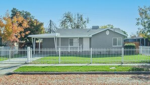 A single-story house with a white picket fence, a covered porch, and a well-maintained lawn. - Upgraded 3B/2Bth w DinningR on Peaceful Street (Fresno)