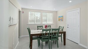 A dining area with a table and four chairs, a white door, and a window with blinds. - Upgraded 3B/2Bth w DinningR on Peaceful Street (Fresno)
