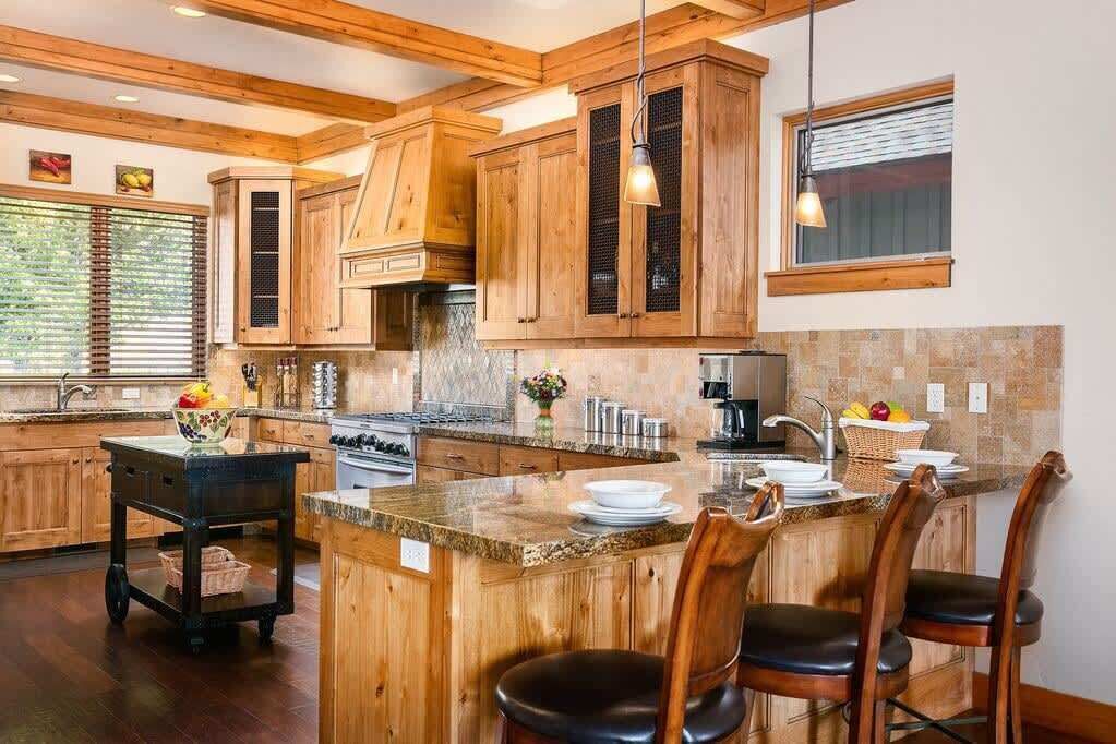 A kitchen with wooden cabinets, a granite countertop, and a central island with bar stools.
