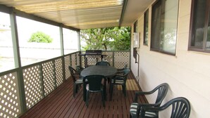 A covered outdoor patio with a table and chairs, a grill, and a view of the street. - Reel Em Inn - Esplanade position.  Winter off peak special! (Point Turton)