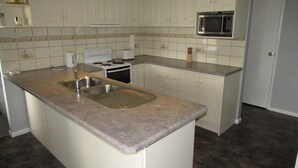 A kitchen with white cabinets, a granite countertop, a stainless steel sink, a microwave, and a stove. - Reel Em Inn - Esplanade position.  Winter off peak special! (Point Turton)
