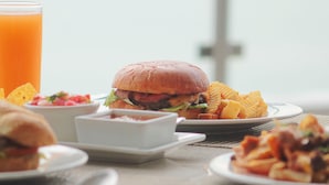Eine Mahlzeit mit einem Burger, Pommes und einem Glas Orangensaft auf einem Tisch.