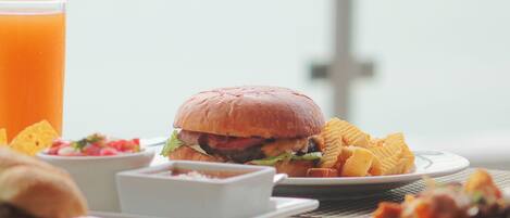 Un repas composé d’un hamburger, de frites et d’un verre de jus d’orange, le tout sur une table.