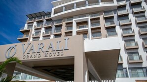 Ein modernes Hotel mit einem auffälligen Schild, auf dem 'VARALI GRAND HOTEL' steht.