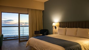 Ein Hotelzimmer mit einem großen Bett, einem Schreibtisch, einem Stuhl und Meerblick.