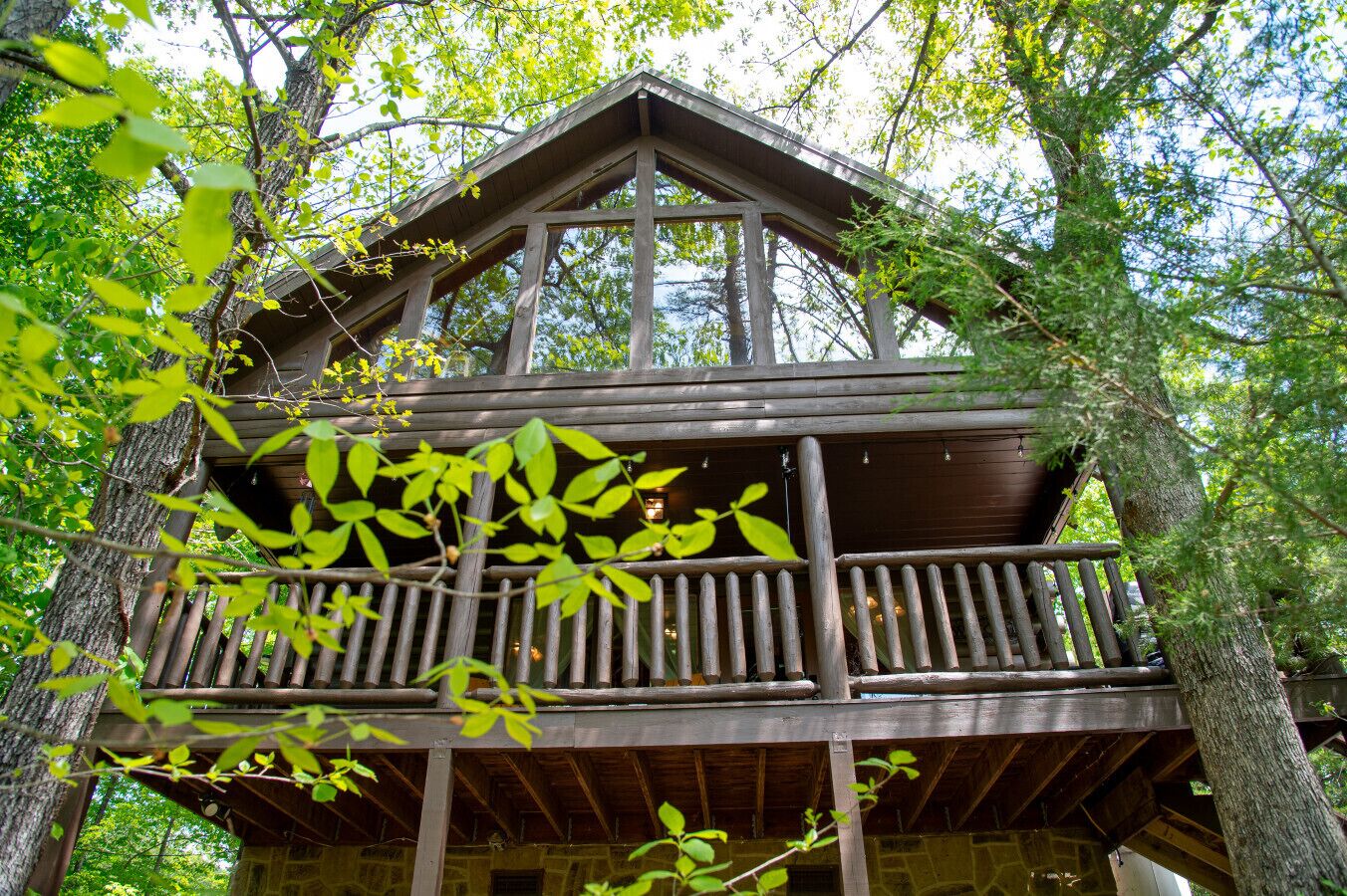 A wooden cabin with a balcony, surrounded by trees.
