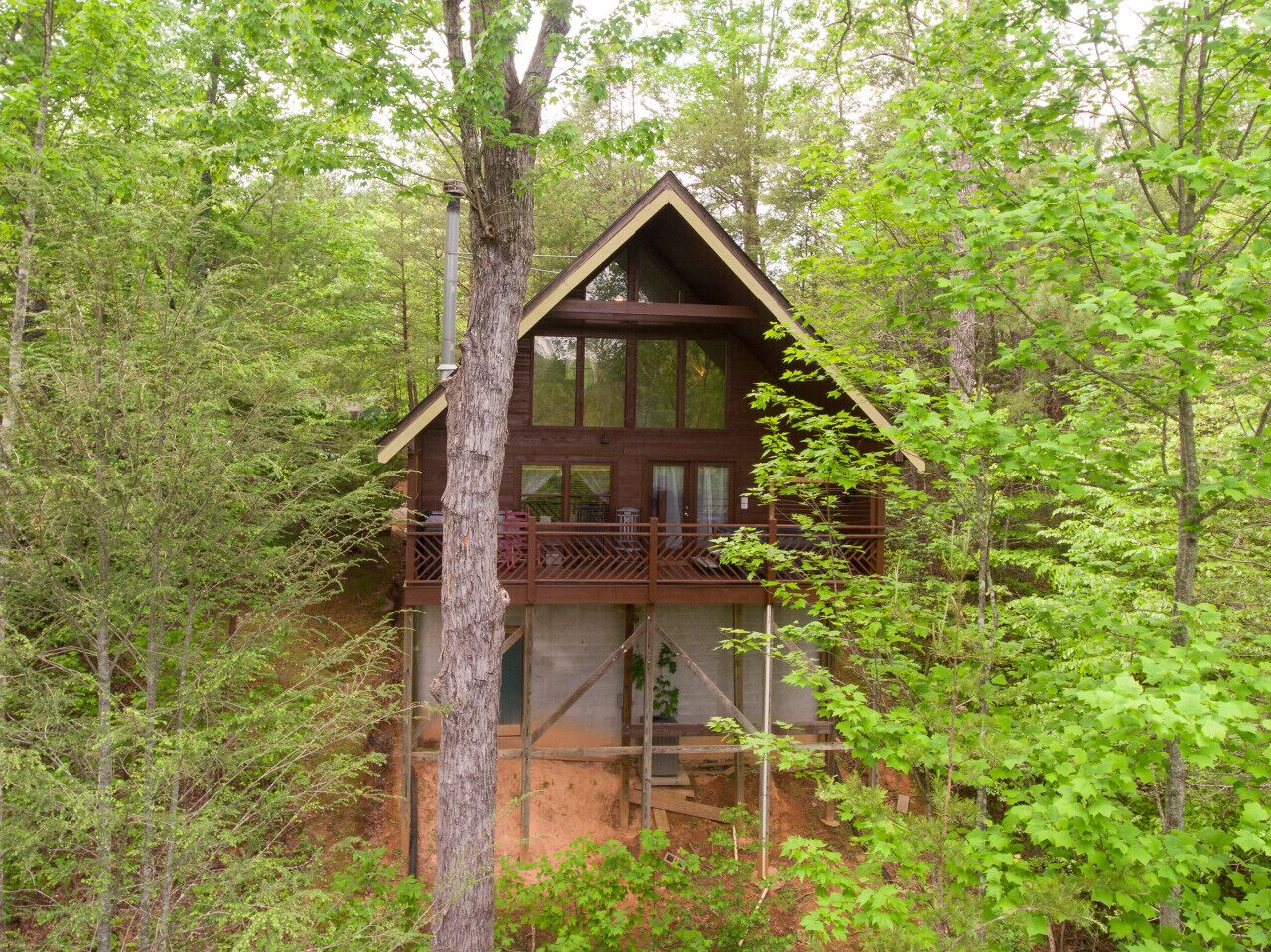 Une cabane dotée d’un balcon, entourée d’arbres.