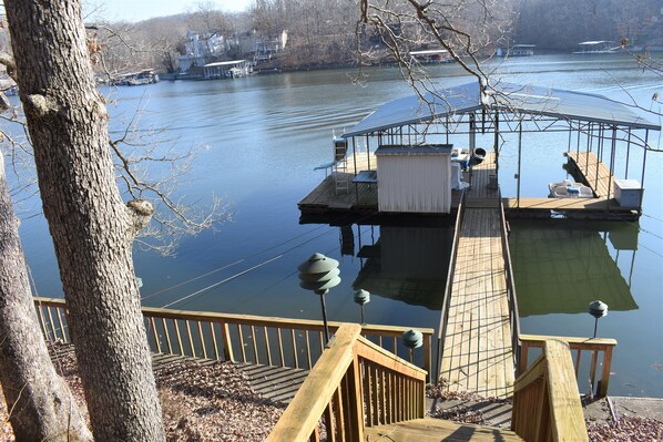 A dock with a covered seating area, a small shed, and a boat.