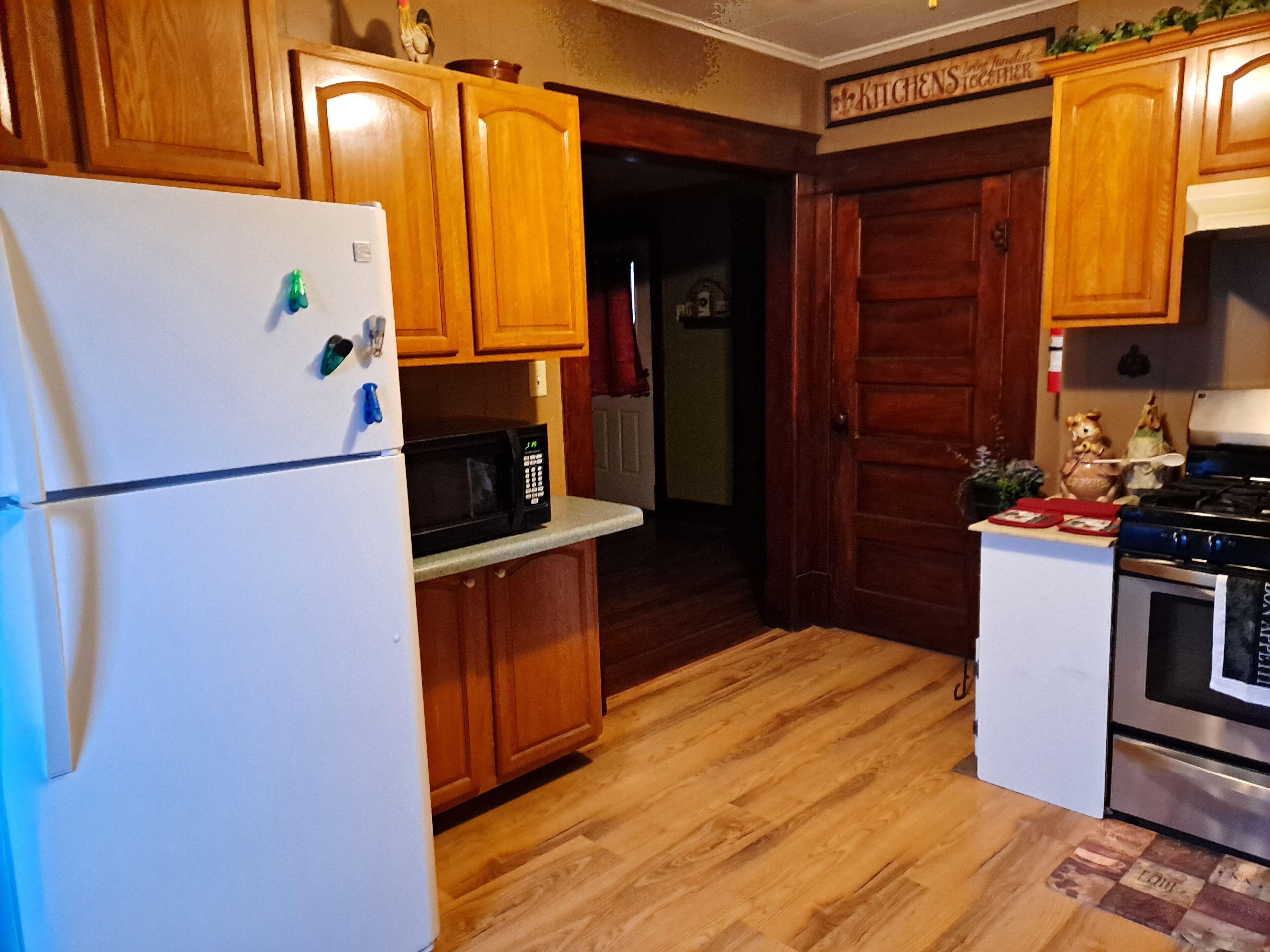 A kitchen with wooden cabinets, a white refrigerator, a black microwave, and a stove.