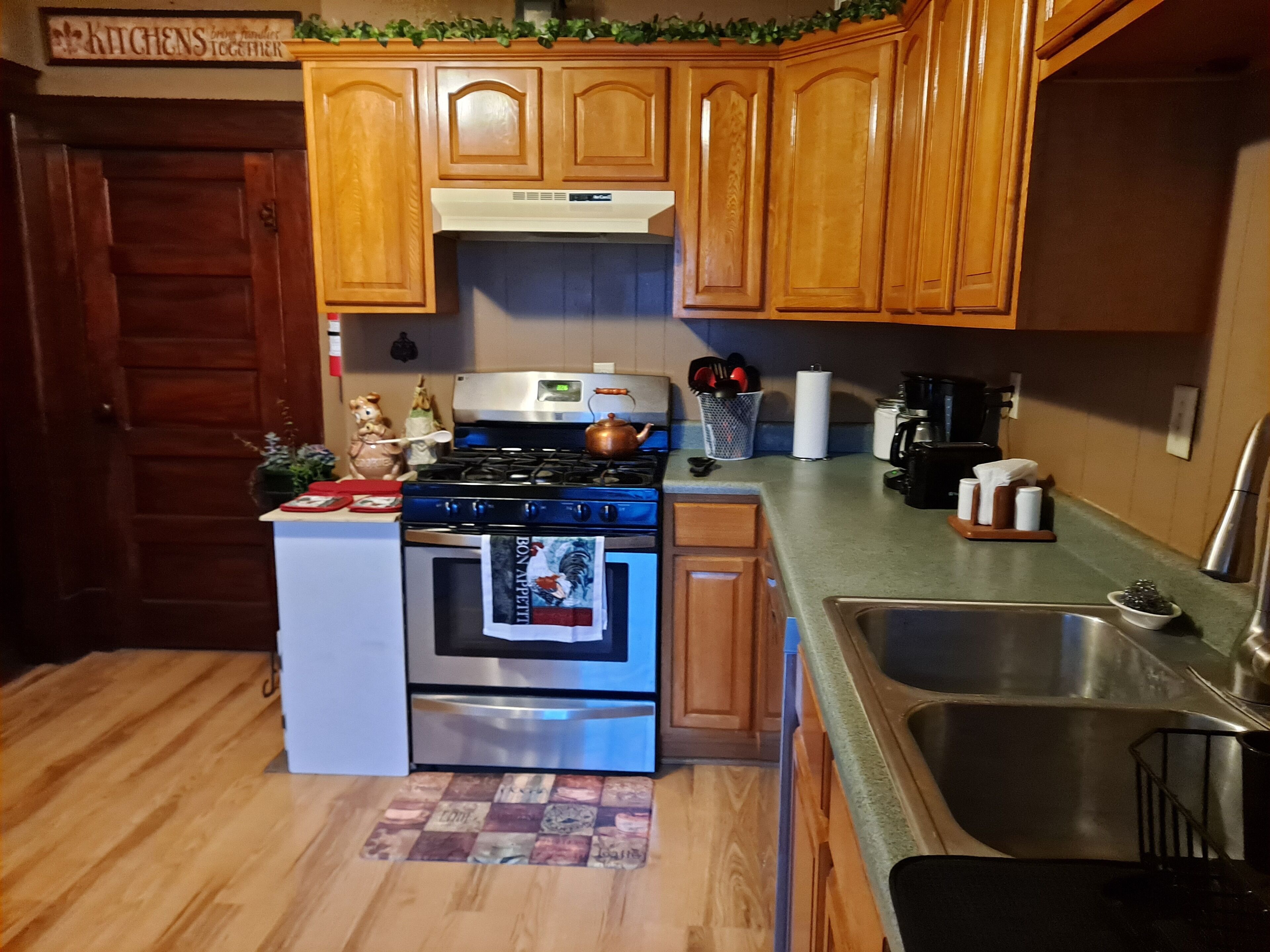 A compact kitchen with wooden cabinets, a stainless steel stove, and a sink.