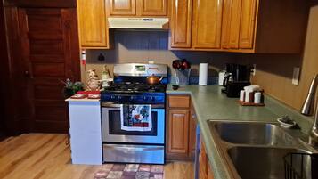 A compact kitchen with wooden cabinets, a stainless steel stove, and a sink.