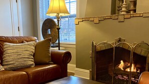 Un salon chaleureux avec une cheminée, un canapé en cuir et un tapis à motifs.