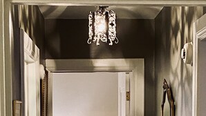 Un couloir avec une lampe, un miroir et une porte donnant sur une autre pièce.