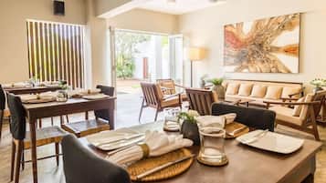 A dining area with a table set for two, a sofa, and a large abstract painting on the wall.