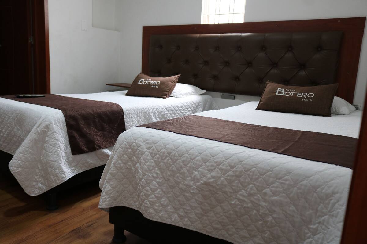 Two single beds with headboards, each with a pillow and a brown bedspread.