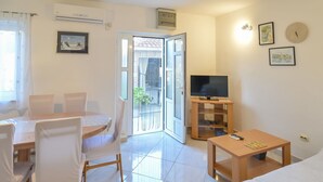A living room with a sofa, a TV on a stand, a dining table with chairs, and a sliding glass door leading to a balcony. - Nice apartment for 4 people with A/C, WIFI, TV and terrace (Solin)