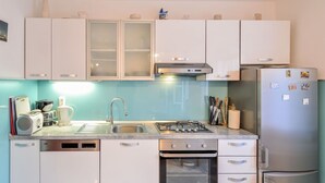 A modern kitchen with white cabinets, a stainless steel stove, and a built-in oven. - Nice apartment for 4 people with A/C, WIFI, TV and terrace (Solin)
