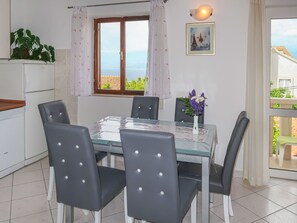 A dining area with a table and chairs, a window with curtains, a plant on the counter, and a framed picture on the wall. - Lovely apartment for 5 guests with A/C, WIFI, TV and balcony (Solin)