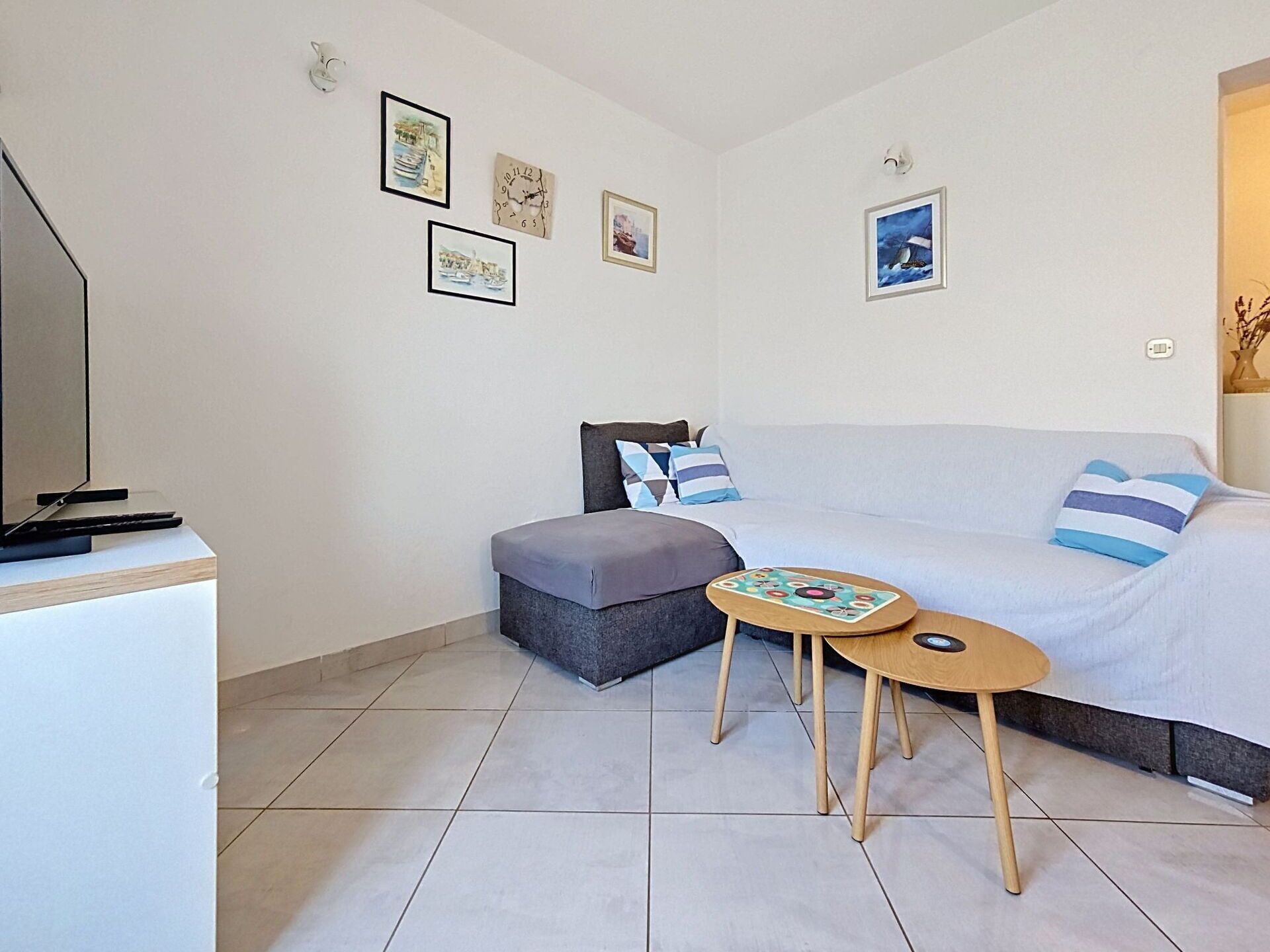 A small, modern bedroom with a bed, a sofa, a small table, and a television.