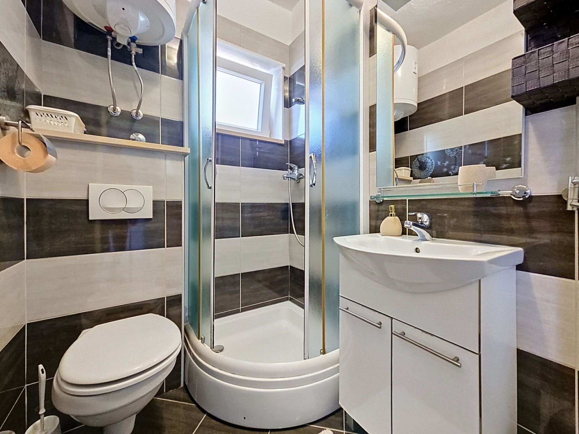 A modern bathroom with a glass-enclosed shower, a white sink, and a toilet.
