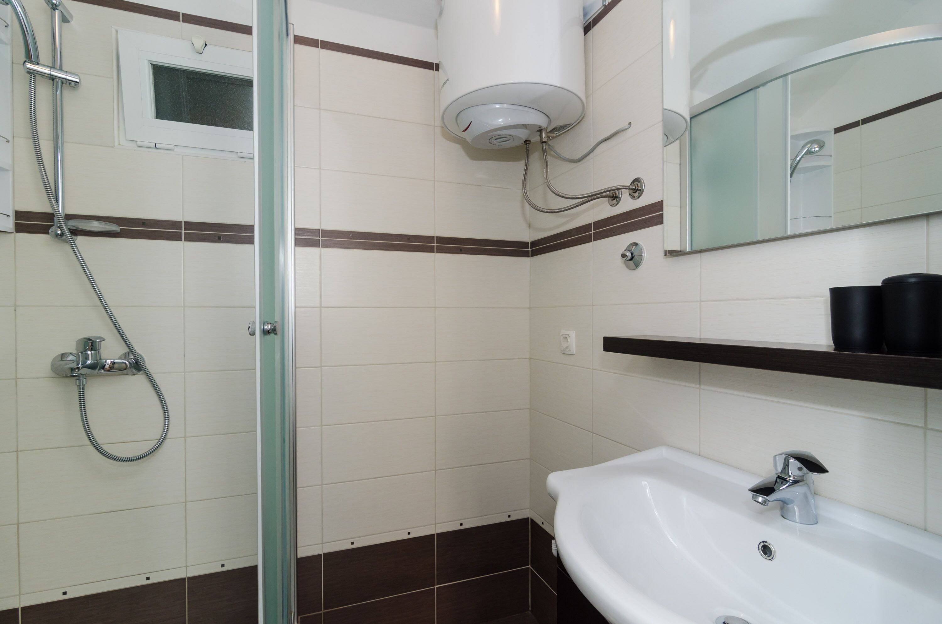 A modern bathroom with a glass-enclosed shower, a white sink, and a mirror above the sink.