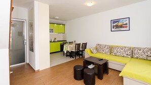 Een woonkamer met een bank, een salontafel en een eethoek met stoelen en een tafel.