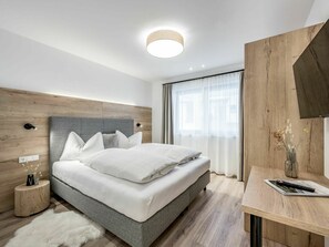 Relax in a serene space with a large bed, bedside tables, and a flat-screen TV.