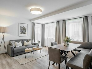 Relax in this stylish living room with a grey sofa, armchair, and minimalist dining table.