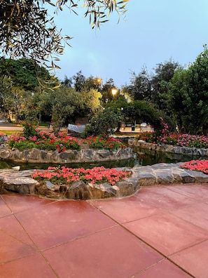 A garden with a stone pathway, flowering plants, and a pond.