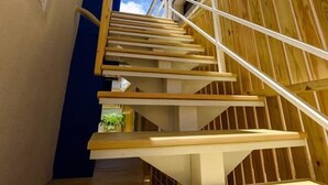 A wooden staircase leading up to a building with a blue door and windows. - Summer Homestay (Magong)