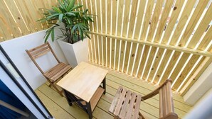 A small wooden deck with a table and two chairs, a potted plant, and a wooden fence. - Summer Homestay (Magong)