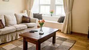 Un salon avec un canapé, une table basse et une fenêtre avec des rideaux.