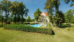 A large, two-story house with a swimming pool in the front yard.