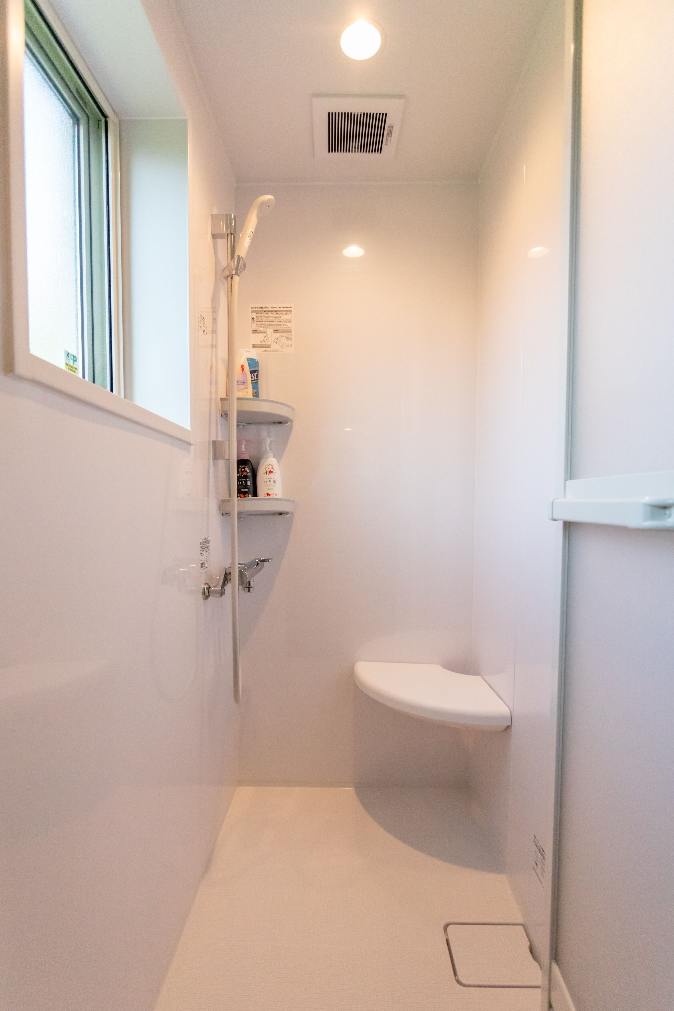 Un bagno piccolo e moderno con doccia, WC e una finestra che permette l'ingresso della luce naturale.
