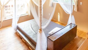 Una cama con dosel sobre cuatro postes, con una plataforma de madera y una mesita de noche.