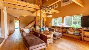 Un amplio espacio de estar con piso de madera, una gran mesa de comedor de madera y un cómodo conjunto de asientos.