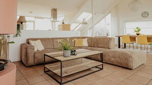 Una sala de estar moderna con un sofá modular, una mesa de centro y un comedor con sillas amarillas.