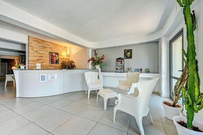 A reception area with a white counter, several white chairs, and a large cactus plant. - Residence Hoteliere En Aparte (Porto-Vecchio)